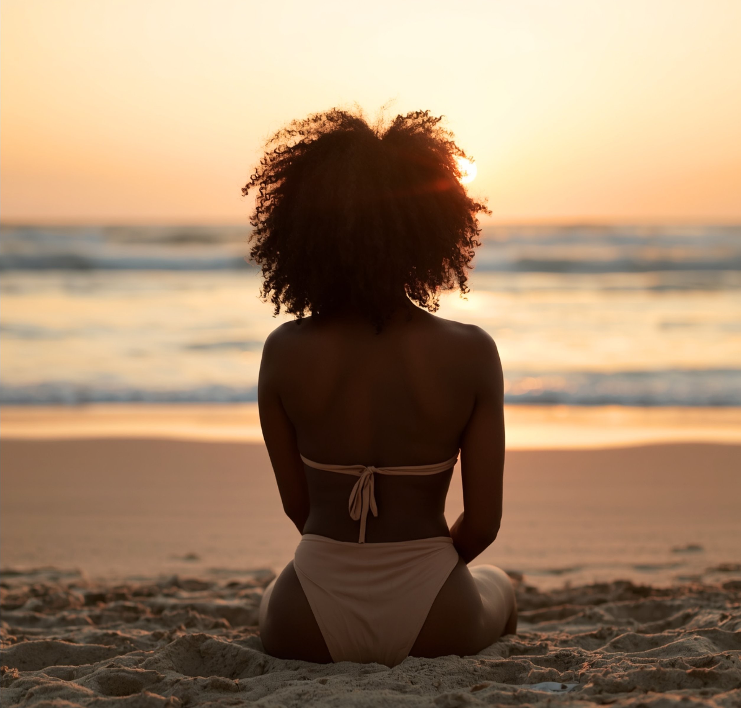 Woman sitting peacefully on the beach at sunset